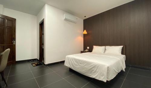a bedroom with a white bed and a brown wall at HighLight House Hotel & Coffee in Pleiku