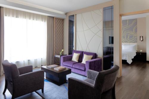a living room with a purple couch and two chairs at Radisson Collection Muscat, Hormuz Grand in Muscat