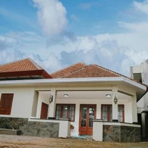 a white house with a red roof at Musafir Guest House Syariah in Solo