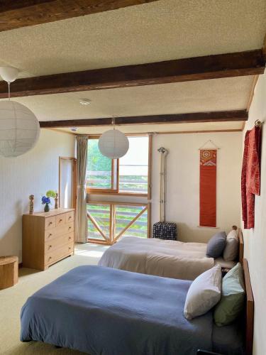 a bedroom with two beds and a large window at Yamadasan Ski Lodge - Madarao in Madarao Kogen