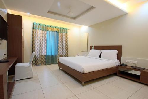 a bedroom with a bed and a desk and a television at Hotel Sheela Shree Plaza in Jhānsi