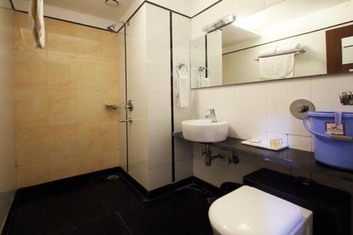 y baño con aseo, lavabo y ducha. en Hotel Sheela Shree Plaza, en v