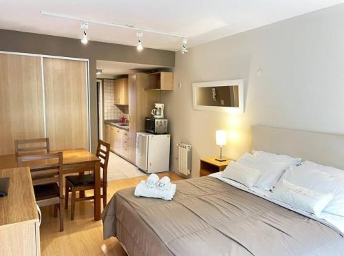 a bedroom with a bed and a table and a kitchen at Apart 460 in San Carlos de Bariloche