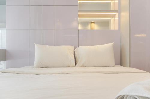 a white bed with white pillows on it at Compact Studio at Tokyo Riverside PIK 2 Apartment By Travelio in Rawalembang