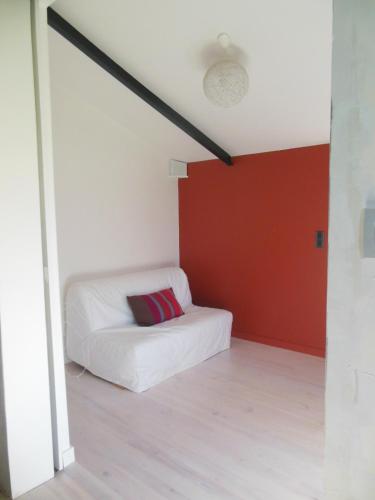 une chambre avec un lit blanc et un mur rouge dans l'établissement Maison dans un ecrin de verdure au pied de la ville, à Auch
