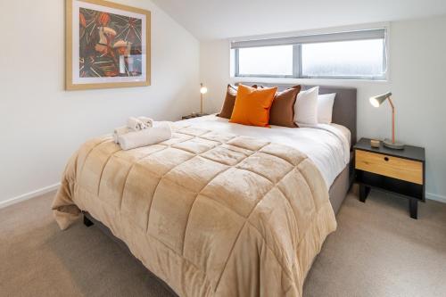 a bedroom with a large bed with orange pillows at Spacious Stay near Avon River with Carpark in Linwood
