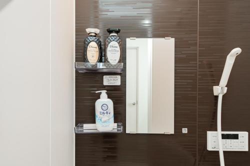 a bathroom with three bottles of soap and a mirror at Momo-stay Ikebukuro in Tokyo