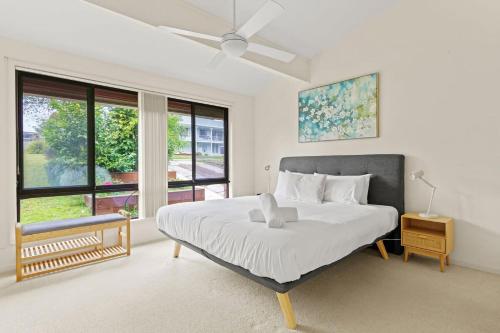 a bedroom with a bed and a large window at Waterfront Pet Friendly Abode Toukley NSW in Toukley