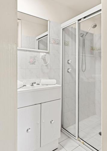 a white bathroom with a shower and a sink at Waterfront Pet Friendly Abode Toukley NSW in Toukley