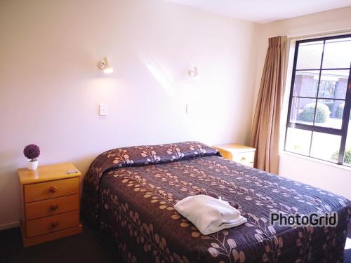 a bedroom with a bed and a window at Aston Court Motel in Blenheim