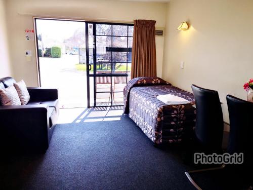 a hotel room with a bed and a sliding glass door at Aston Court Motel in Blenheim