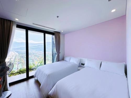 a bedroom with two beds and a large window at Flamingo1 Ibiza Hai Tien in Nam Khê