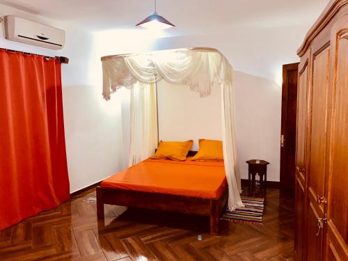 a bedroom with an orange bed with a canopy at Appartement T4 Standing Diégo-Suarez in Antsiranana