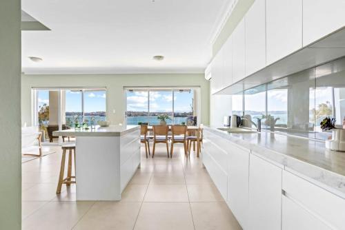 a kitchen with white cabinets and a table with chairs at Ocean Front Luxury The Lambeth Walk in Bundeena