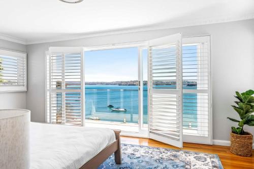 a bedroom with a large window with a view of the ocean at Ocean Front Luxury The Lambeth Walk in Bundeena