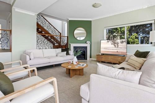 a living room with white furniture and a fireplace at Ocean Front Luxury The Lambeth Walk in Bundeena