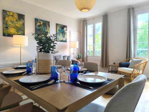 une salle à manger avec une table en bois et des verres bleus dans l'établissement Saint Lazare 2 chambres Spacieux Modulable Confort, à Compiègne