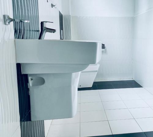 a white bathroom with a toilet and a sink at Seashore Mirissa in Mirissa