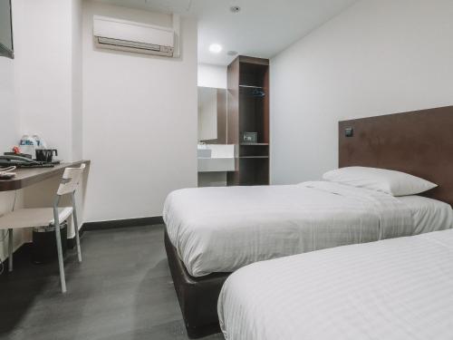 a hotel room with two beds and a table and a desk at A Hotel Desker in Singapore