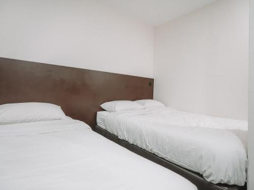 two beds in a room with white sheets and pillows at A Hotel Desker in Singapore