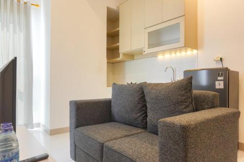 a couch in a living room with a kitchen at Modern Look 2BR Tokyo Riverside PIK 2 Apartment By Travelio in Rawalembang