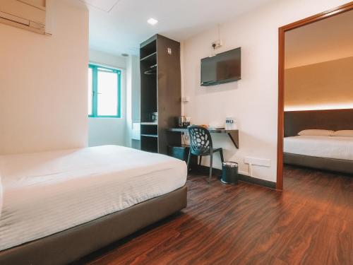 a room with two beds and a desk with a mirror at A Hotel Desker in Singapore