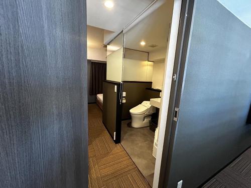a bathroom with a toilet and a glass door at Hotel STARRIZE in Fukuoka
