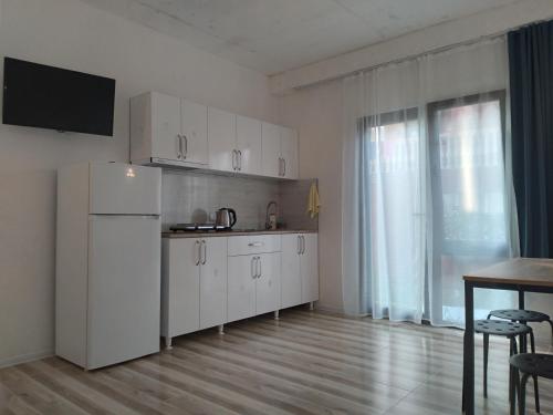 a kitchen with white cabinets and a table in a room at Bambuki in Kuchkisabano