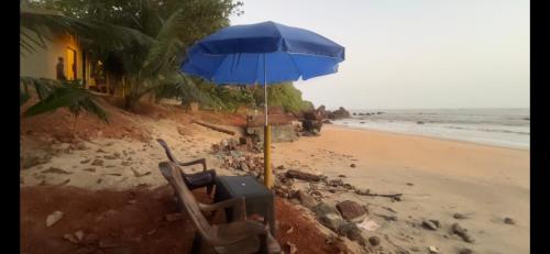 a chair and an umbrella on the beach at Rocks beach house in Kannur