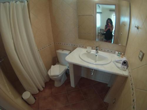 Eine Frau fotografiert ein Bad mit Waschbecken und WC in der Unterkunft Sivota Gold in Syvota