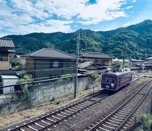 a purple train on the tracks in a city at Mulan Stay 嵯峨嵐山 in Shimo saga