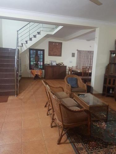 a living room with chairs and a table and stairs at Tropical Blooms by StayApart in Kutta