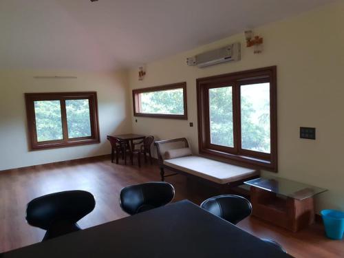 a living room with a table and chairs and windows at Tropical Blooms by StayApart in Kutta