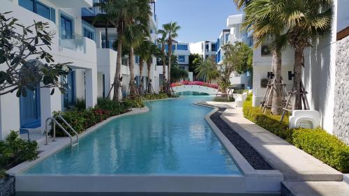 a swimming pool in the middle of a building with palm trees at The Crest Santora Huahin 4 Fl H(Monthly rate) in Hua Hin