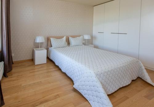a bedroom with a white bed and a white cabinet at DRUSKININKŲ PANORAMA Apartamentai in Druskininkai