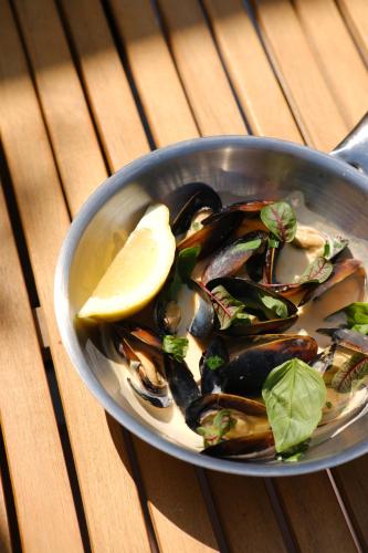 a bowl of mussels with a lemon on a table at Margot Sololaki in Tbilisi City
