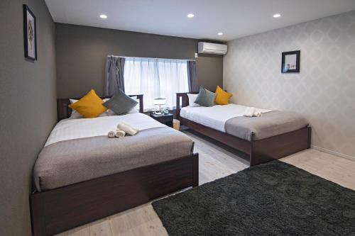 a bedroom with two beds with yellow pillows at 旅タイム・時光　鶴橋駅 in Osaka