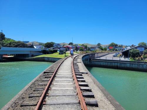 a man walking on a railroad track next to a river at Esplanade Townhouse in Gisborne