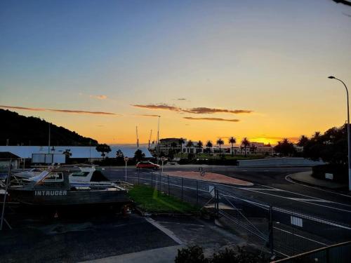 a sunset over a parking lot with a boat at Esplanade Townhouse in Gisborne