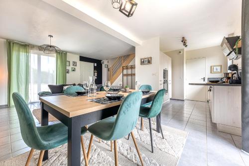 une salle à manger avec une table et des chaises vertes dans l'établissement Maison familiale 6 personnes, à Miniac-Morvan