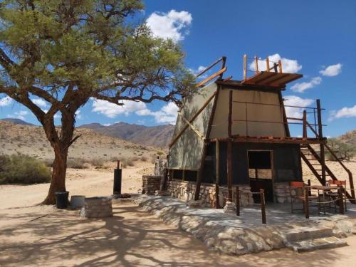 a building in the middle of a desert with a tree at Camp Gecko - PRIVATE NATURE RESERVE; TENTED CAMP AND CAMPSITE in Solitaire