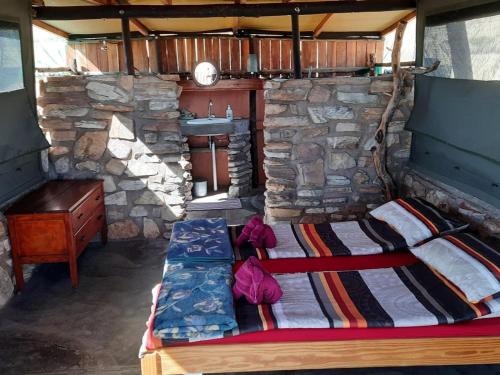 a bedroom with a bed and a desk in a stone house at Camp Gecko - PRIVATE NATURE RESERVE; TENTED CAMP AND CAMPSITE in Solitaire