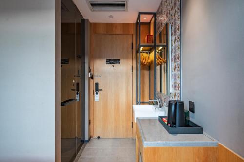 a bathroom with a sink and a mirror and a door at Qiuguo Hotel Beijing Convention Center Bird's Nest Beiyuan in Beijing