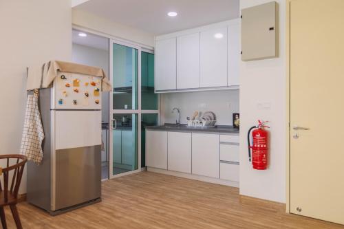 a kitchen with white cabinets and a refrigerator at NaiBnB in Impiria Residensi in Klang