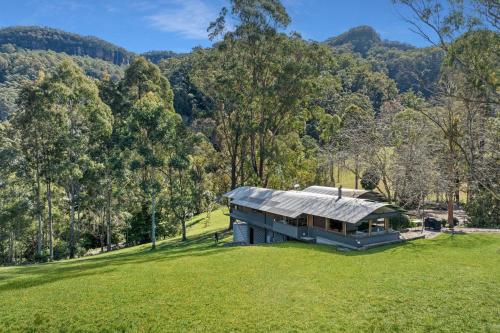 a house in the middle of a field with trees at Kangaroo River Hideaway, Kangaroo Valley in Upper Kangaroo River