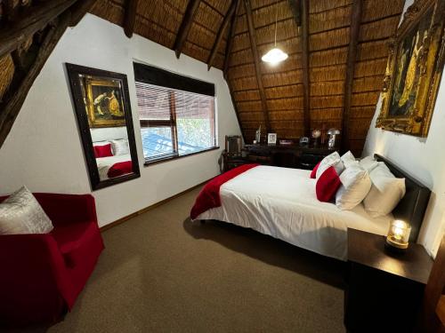 a bedroom with a large bed and a red chair at Blue Gum Cottage in Midrand