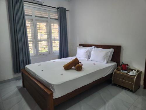 a bedroom with a large bed with white sheets and a window at Spring Villa Neluwa in Nelluwa