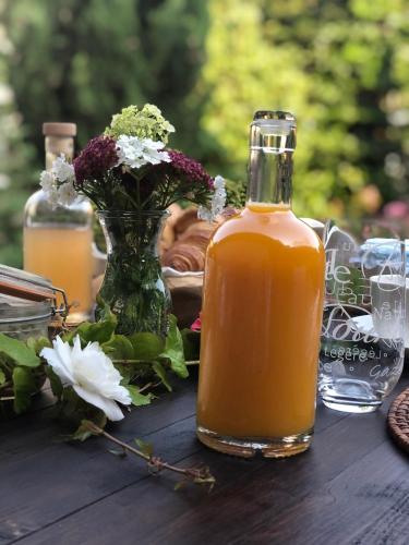 La suite des Chapitres en Champagne في Courmas: زجاجة عصير برتقال على طاولة خشبية مزينة بالزهور