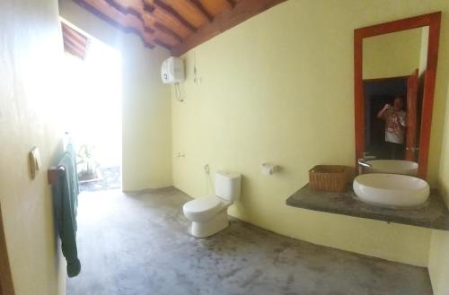 a bathroom with a toilet and a sink and a mirror at Kambuna Bungalow in Krui