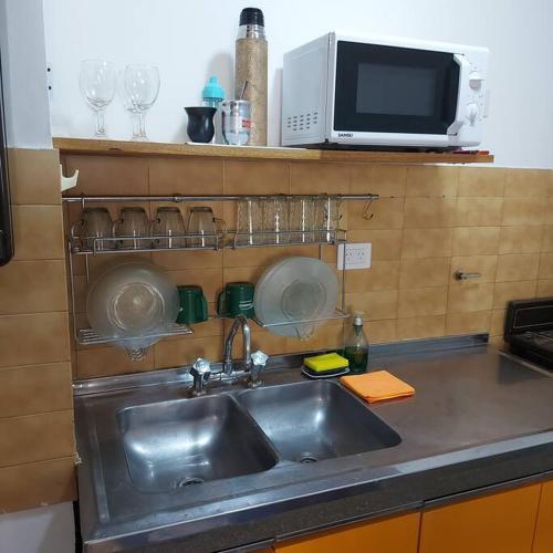 eine Küchentheke mit Spüle und Mikrowelle in der Unterkunft Microcentro de la Docta in Cordoba